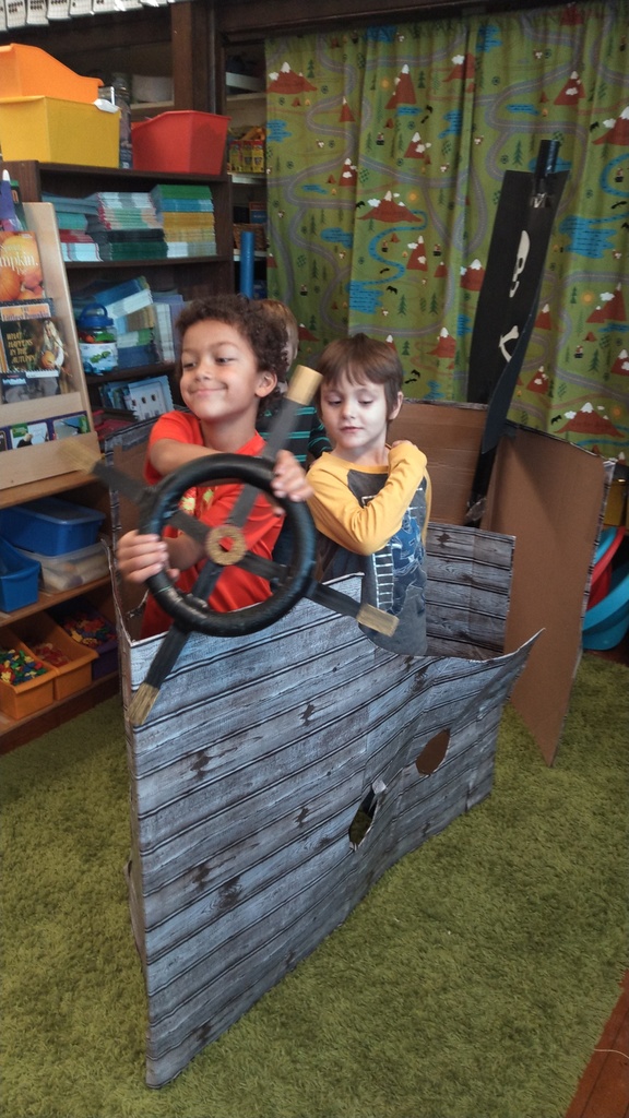 2 boys playing in cardboard pirate ship