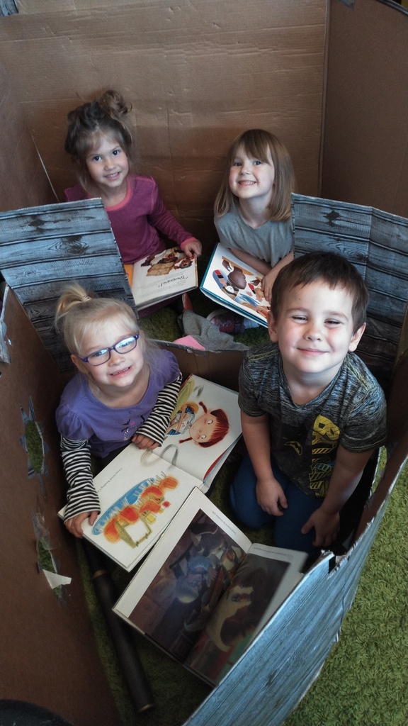 students reading books in a cardboard pirate ship