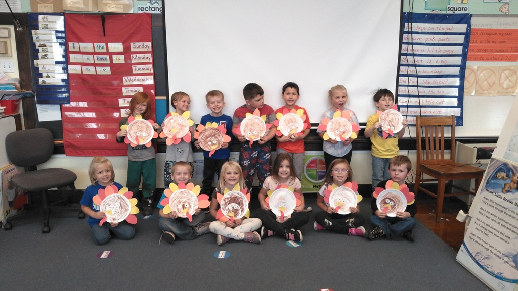 Kindergarten students holding drawings of turkeys