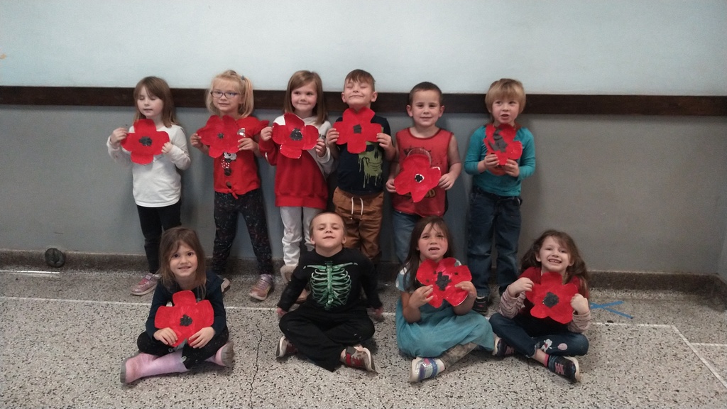 kindergarten students holding red poppy crafts