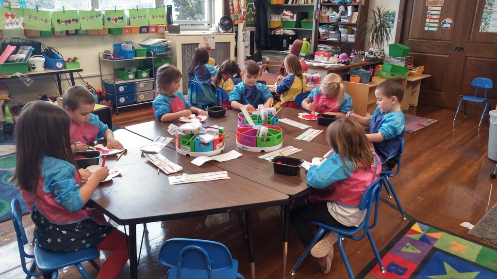 Kindergarten students painting red poppies out of paper plates