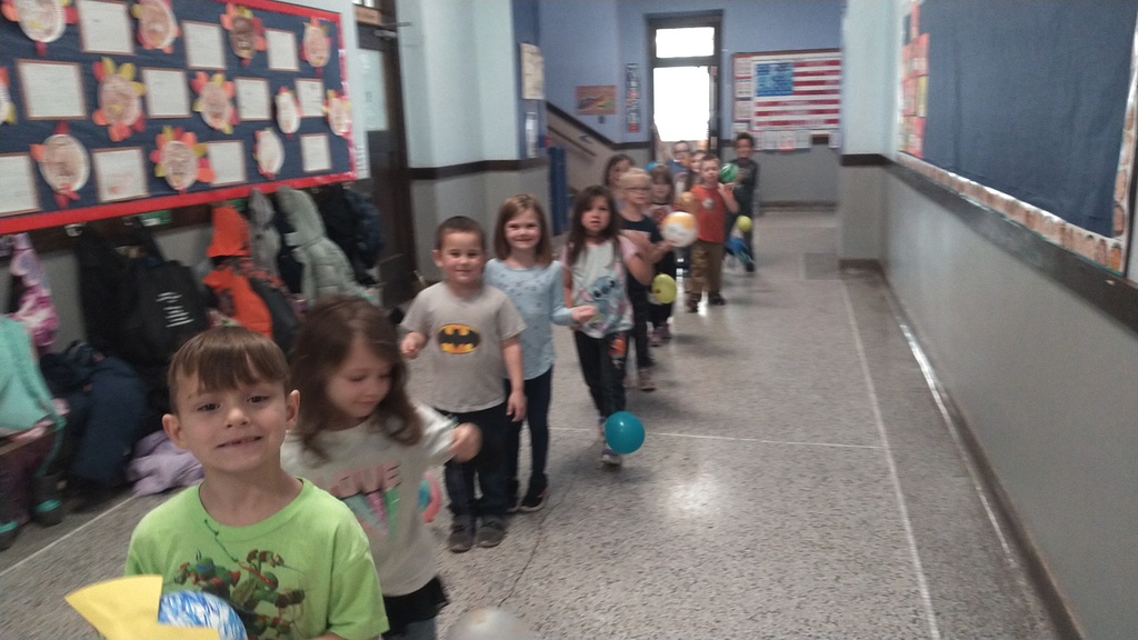 Kindergarten students walking hallway with balloons