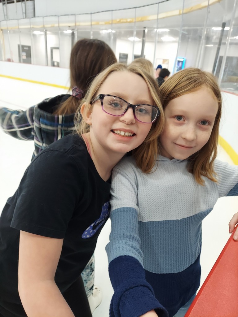 2 girls, smiling at skating rink